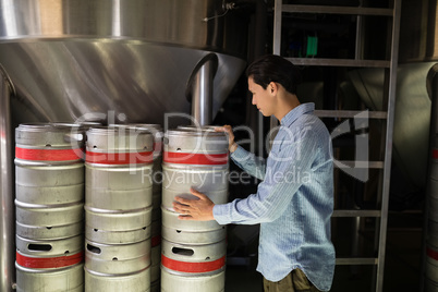 Manager checking beer keg in warehouse