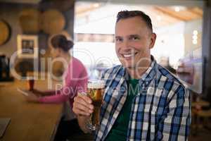 Portrait of smiling man having glass of beer at bar counter
