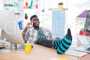 Male executive talking on mobile phone while relaxing at his desk in office