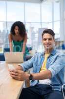 Male executive using mobile phone while female executive working on computer