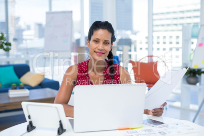 Female executive holding documents while working at desk