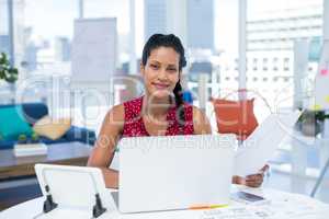 Female executive holding documents while working at desk