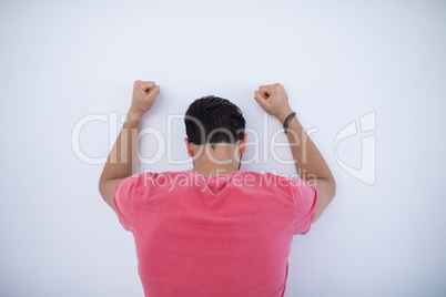 Depressed male executive with arms raised leaning on wall