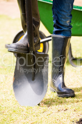Low section of man in rubber boot with shovel