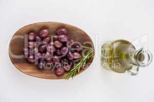 Directly above shot of brown olives in plate by oil in jar