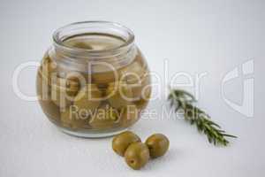 High angle view of green olives in glass jar by herb