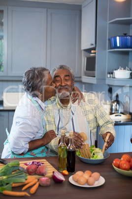 Side view of woman kissing man while preparing food