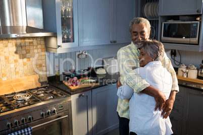 Affectionate couple with eyes closed embracing while standing in kitchen