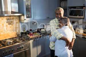 Affectionate couple with eyes closed embracing while standing in kitchen