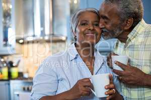 Affectionate man with woman standing in kitchen