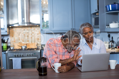 Cheerful man gesturing while woman using laptop