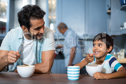 Father and son having breakfast with man in background