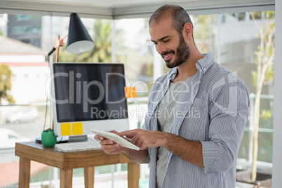 Smiling designer using digital tablet in office