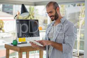 Smiling designer using digital tablet in office