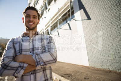 Smiling man with arms crossed standing by building