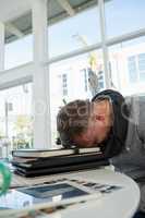 Tired businessman sleeping on files at desk
