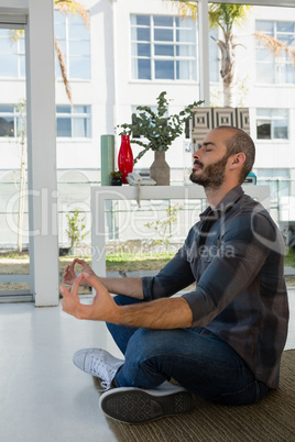 Businessman meditating while sitting on floor