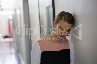 Sad young businesswoman leaning on wall