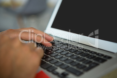 Cropped hands of man using laptop