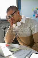 Tired young man looking into laptop in office