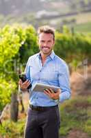 Portrait of smiling man holding wine bottle and tablet