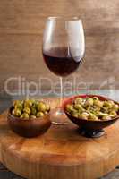 High angle view of olives served in bowls by wineglass on table