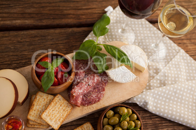 Overhead view of crackers with olives and meat by cheeses