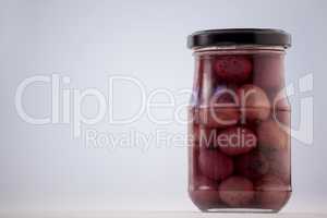 Close up of red olives in glass jar