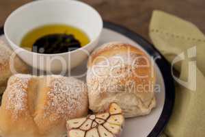 Close up of bread by olive oil in bowl on plate