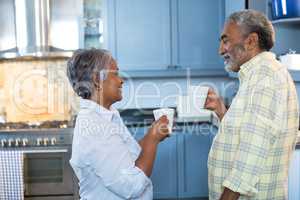 Side view of couple having drink in kitchen