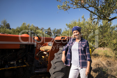 Portrait of confident woman standing near tractor in olive farm