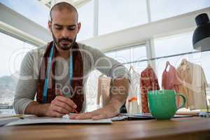 Male designer drawing sketch while sitting at table