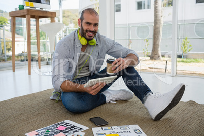 Portrait of designer holding disposable cup and tablet computer