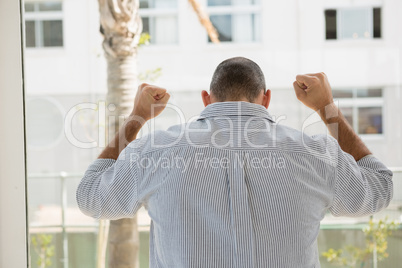 Rear view of frustrated designer standing by glass window