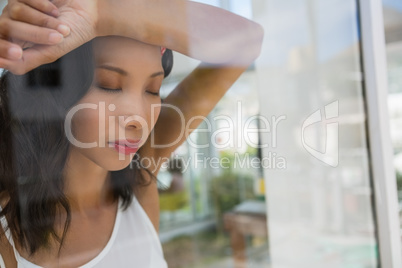Frustrated businesswoman with eyes closed seen through glass