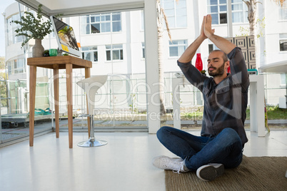 Designer in prayer position meditating while sitting on floor