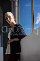 Thoughtful businesswoman looking away while standing by windoew in office