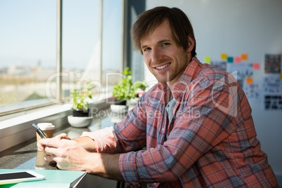 Portrait of smiling man using phone at office