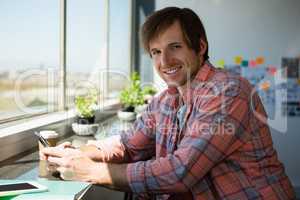 Portrait of smiling man using phone at office