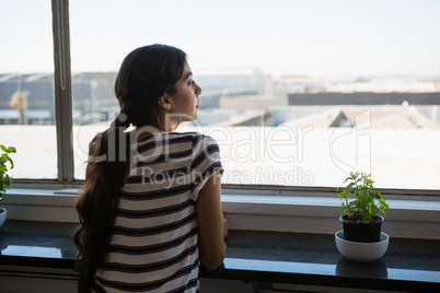 Rear view of woman looking through window at office