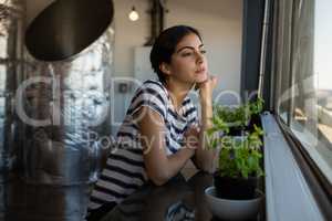 Thoughtful young woman looking through window at office