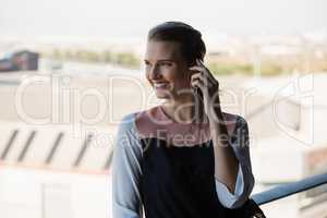 Happy woman talking on mobile phone in balcony at office