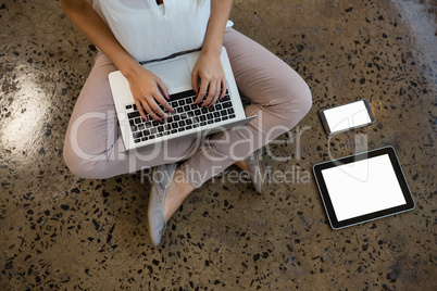 Low section of woman using laptop on floor at office