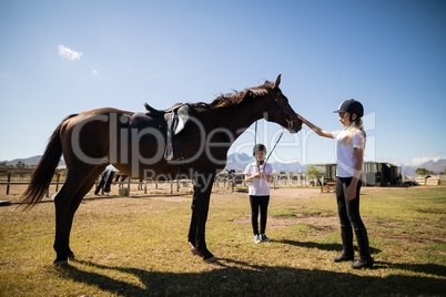 Two girls standing with a horse in the ranch