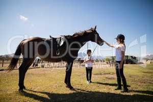 Two girls standing with a horse in the ranch