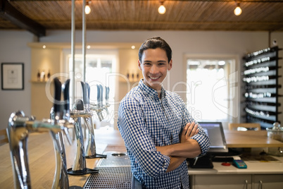 Smiling man with arms crossed at counter in restaurant