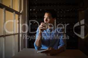 Man having coffee and holding digital tablet in restaurant