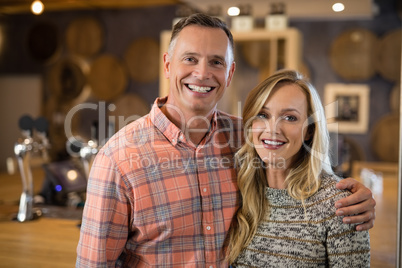 Happy couple standing together with arm around in bar