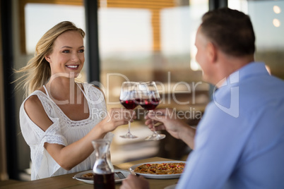 Happy couple toasting wine glass while having meal