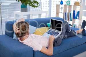 Male executive using laptop while relaxing on sofa